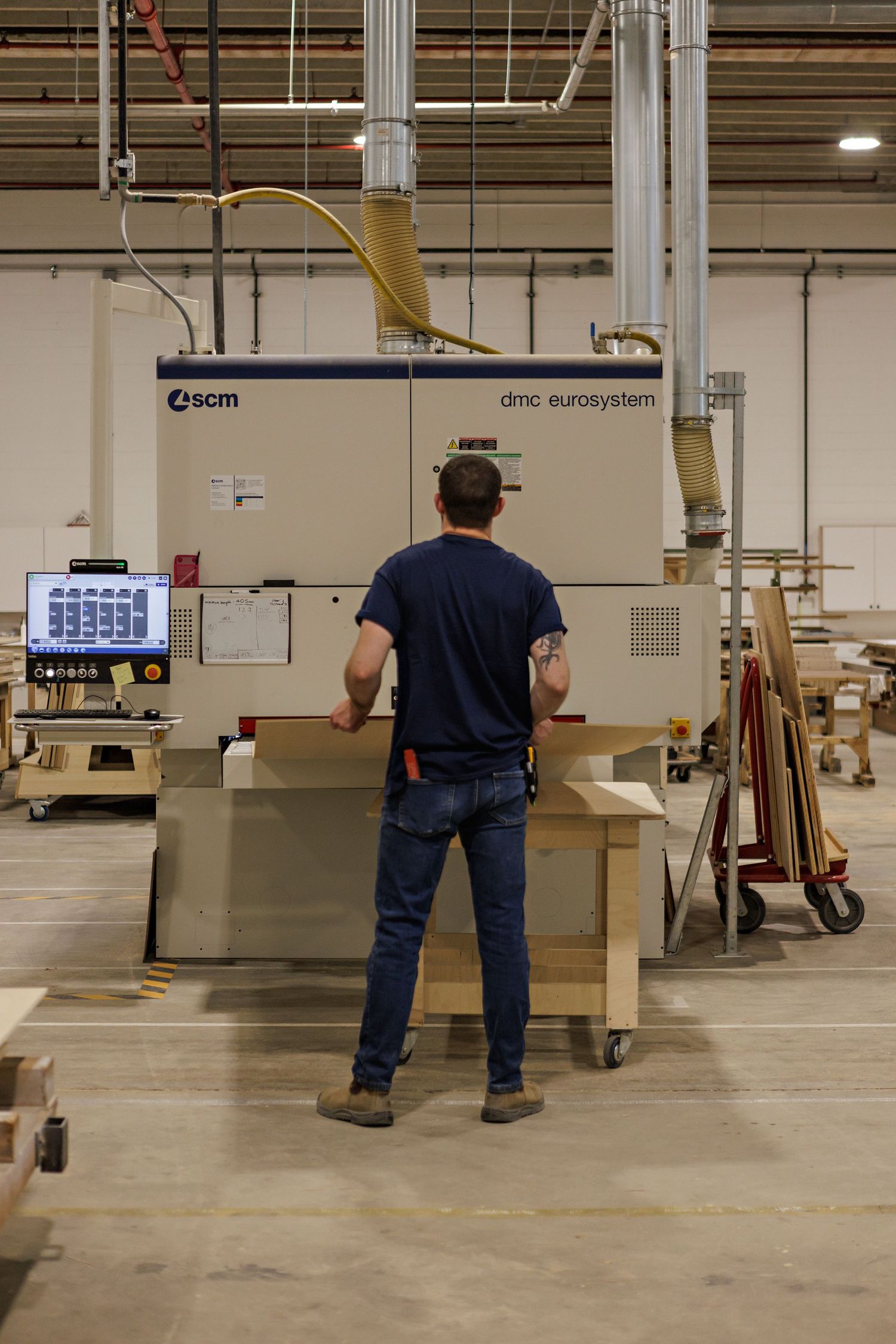 A worker operates a SCM Superset XE CNC machine in a manufacturing facility.