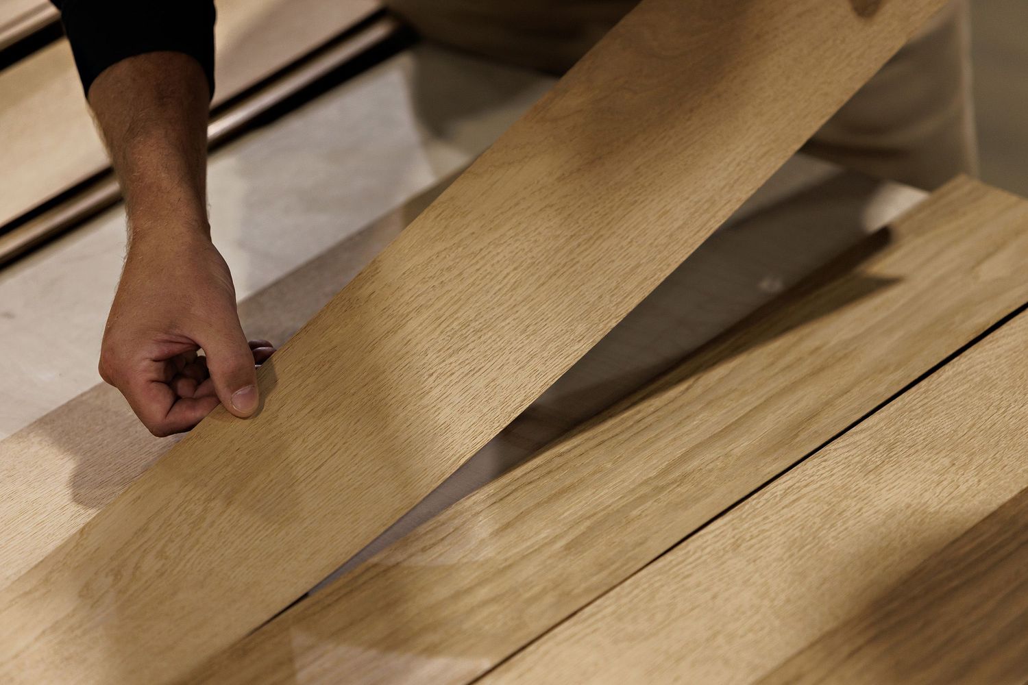 Multiple wooden planks being cut on a table saw surface in sequence for woodworking.