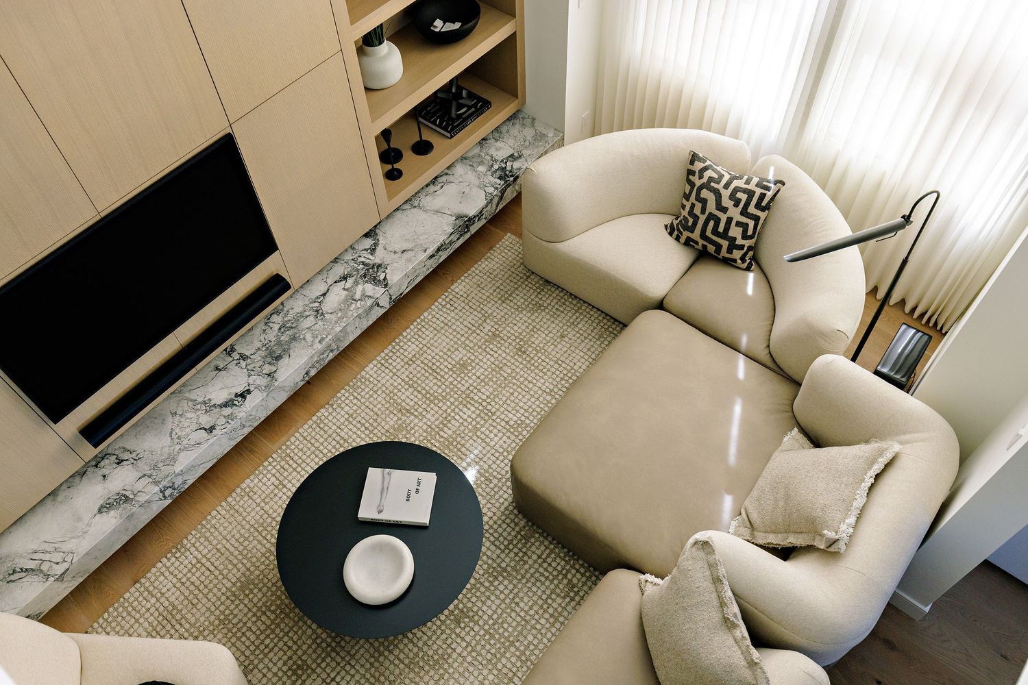 Contemporary living room with cream colored chairs and a black coffee table on a neutral rug.
