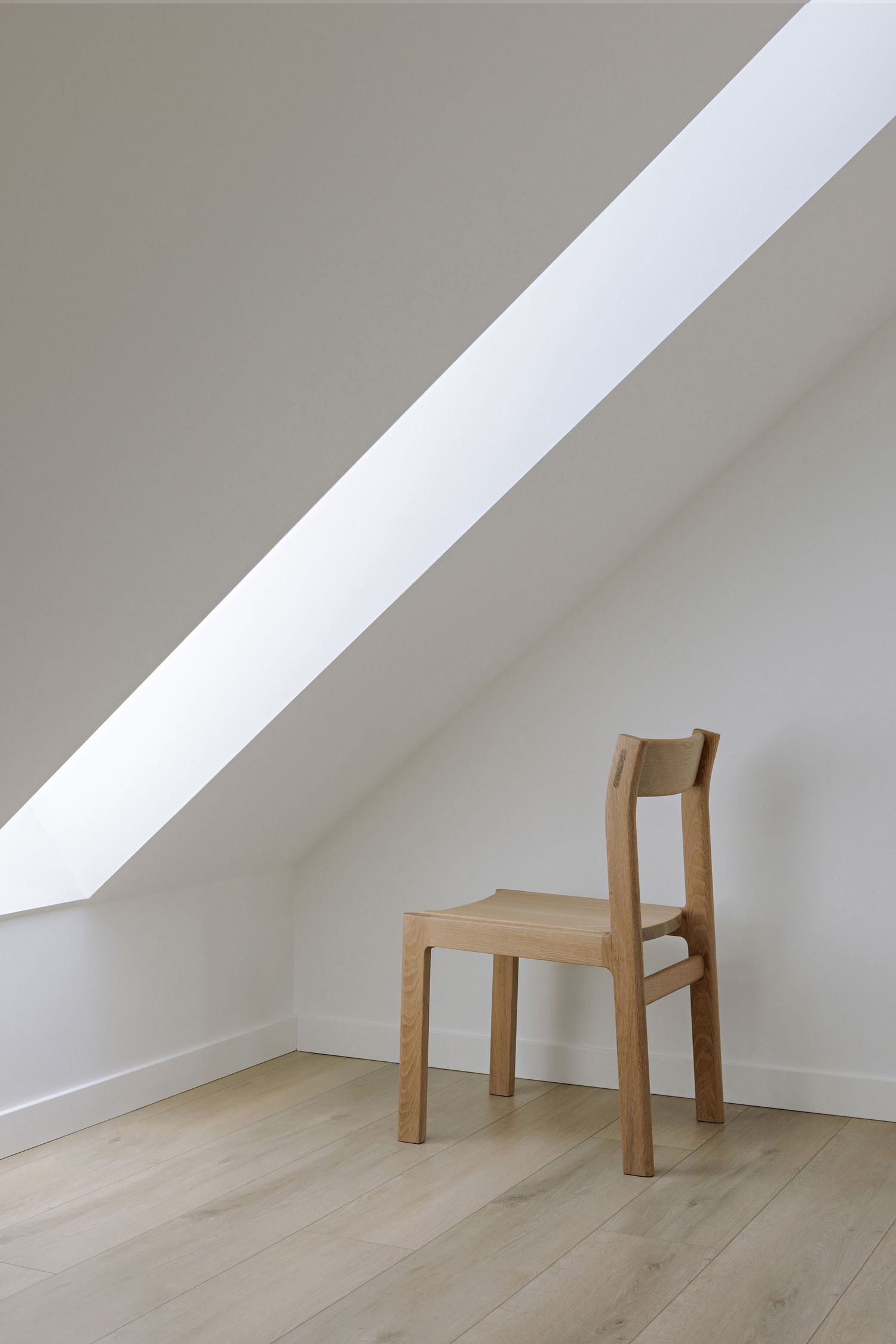 Progressive sequence showing a wooden chair disassembling into pieces against a white wall and light floor.