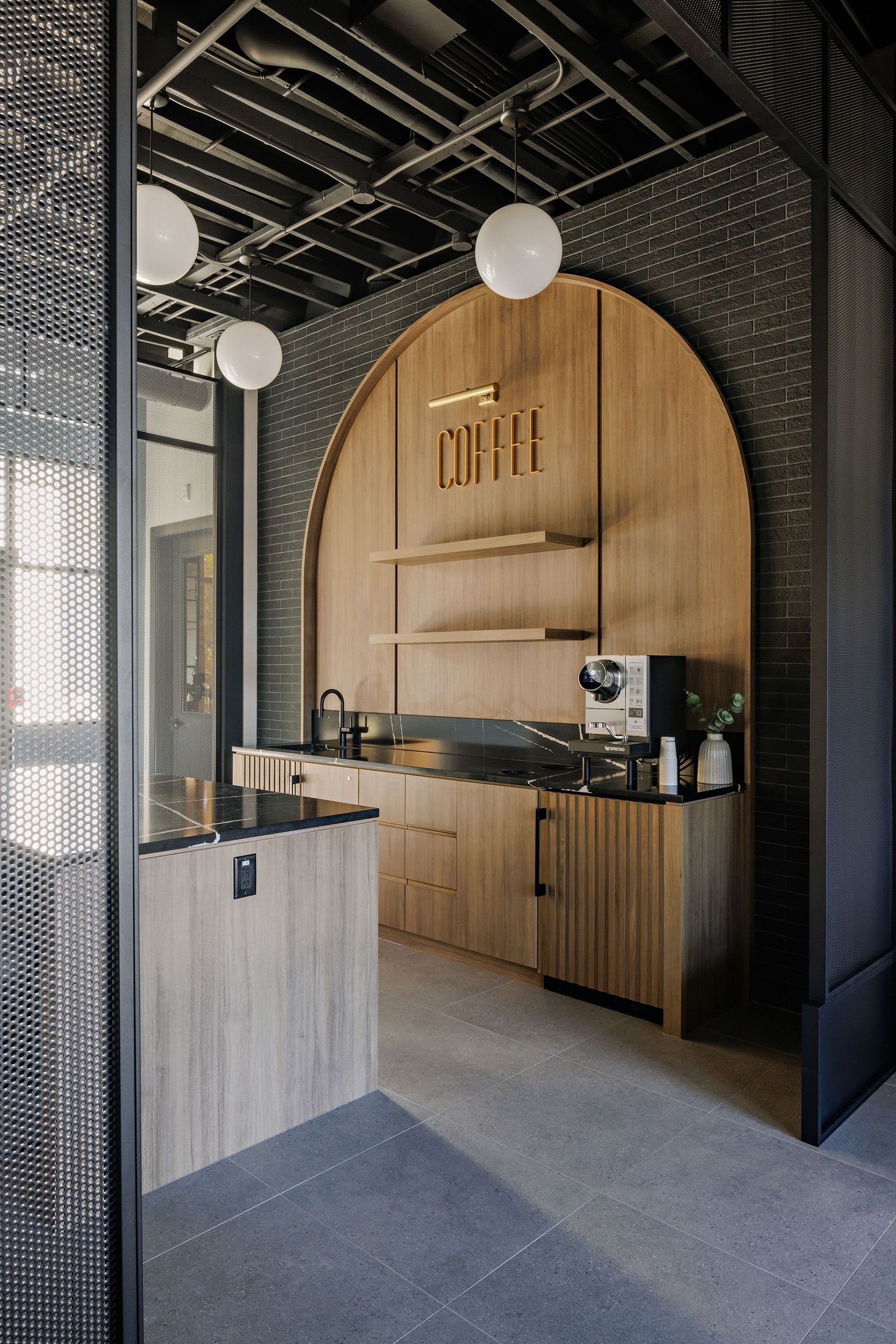 Modern minimalist coffee shop interior with wooden arch feature wall, concrete floors and industrial ceiling details.