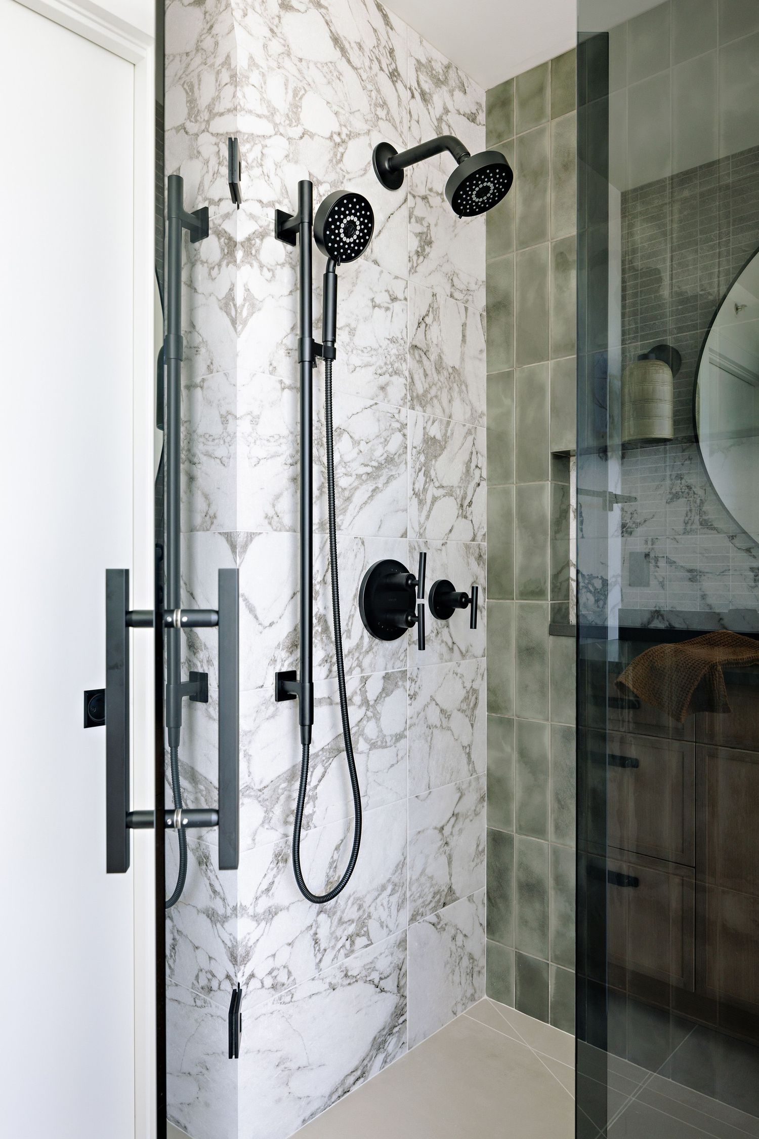 Modern shower interior with marble walls and matte black fixtures including dual shower heads.