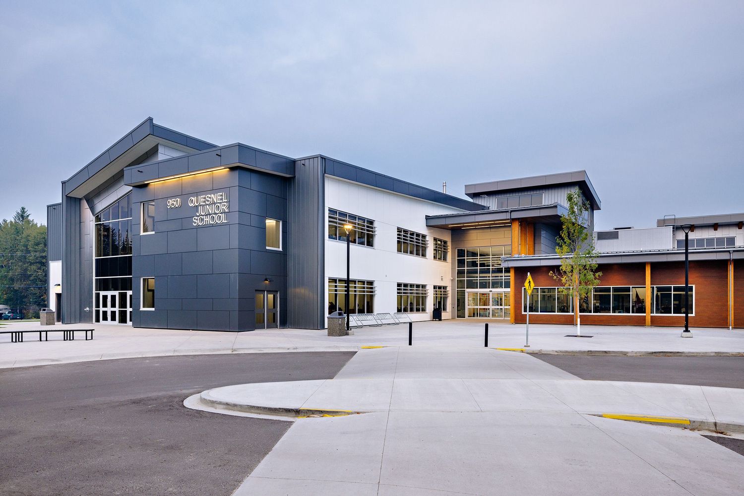 Contemporary school building exterior with dark gray and white siding featuring angular roof lines and large windows.