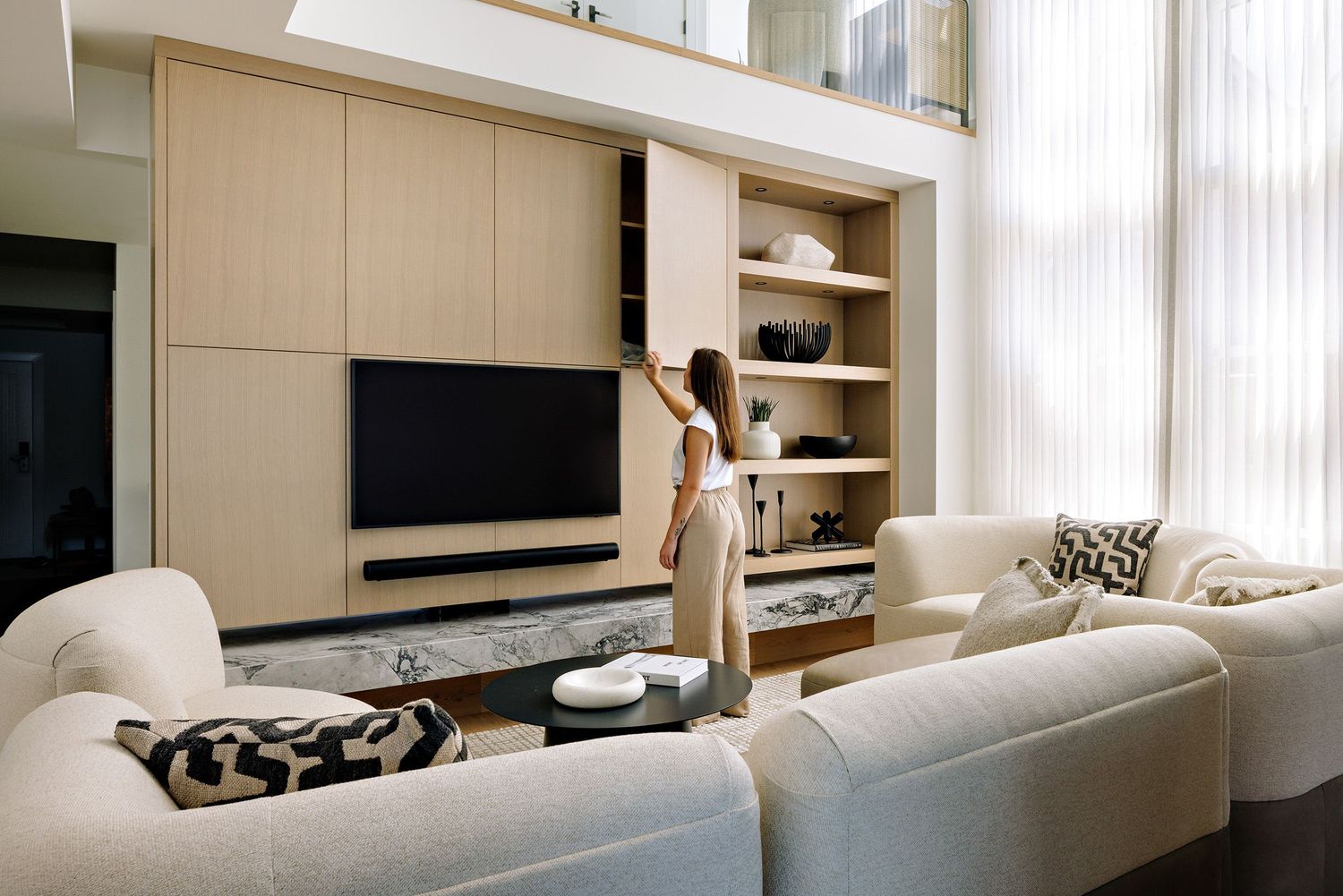 Modern minimalist living room with white built-in shelving, sleek entertainment center, and comfortable seating.