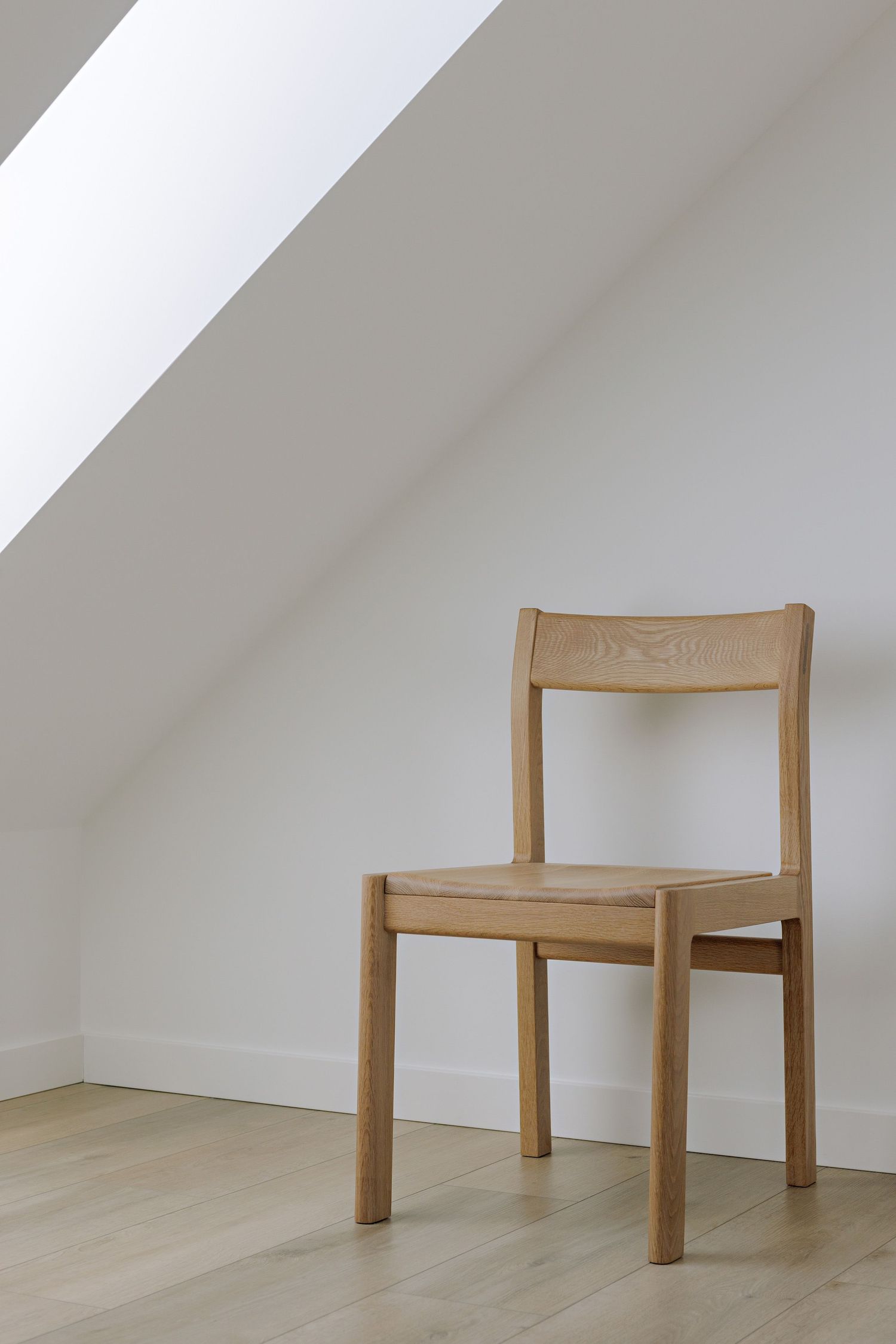 Minimalist wooden chair shown from five different angles against a white wall and light wood floor.