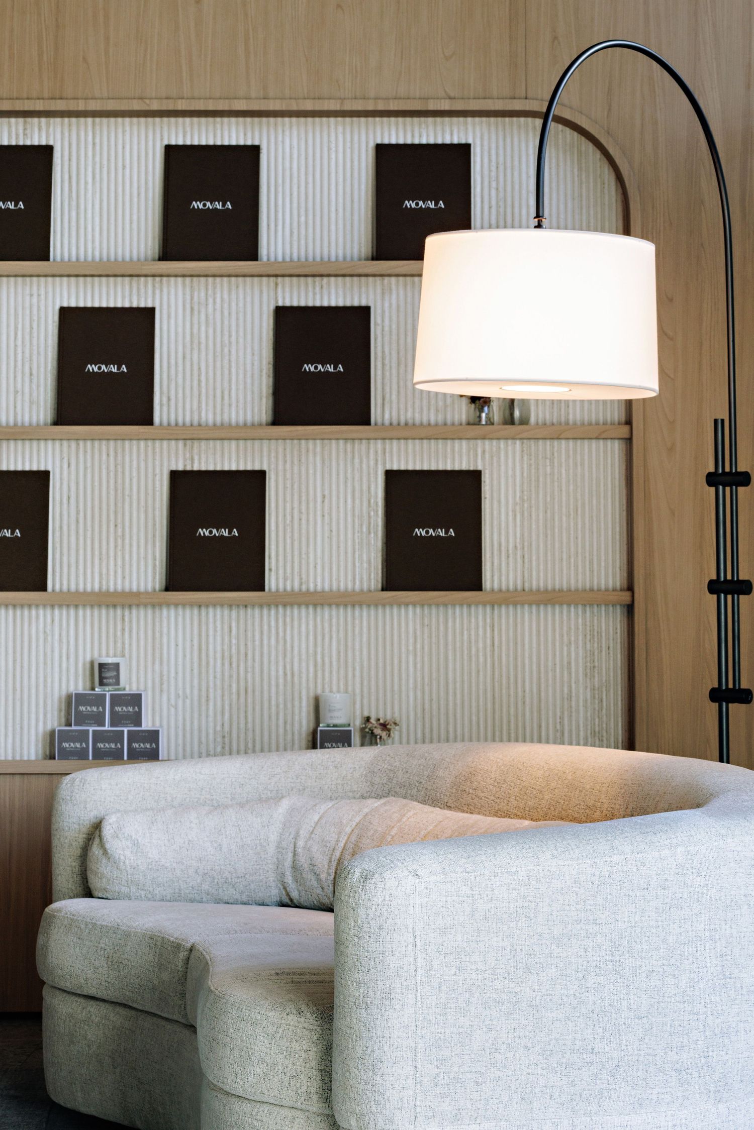 Modern grey armchair with arc floor lamp against wall with black framed artwork arranged in grid pattern.