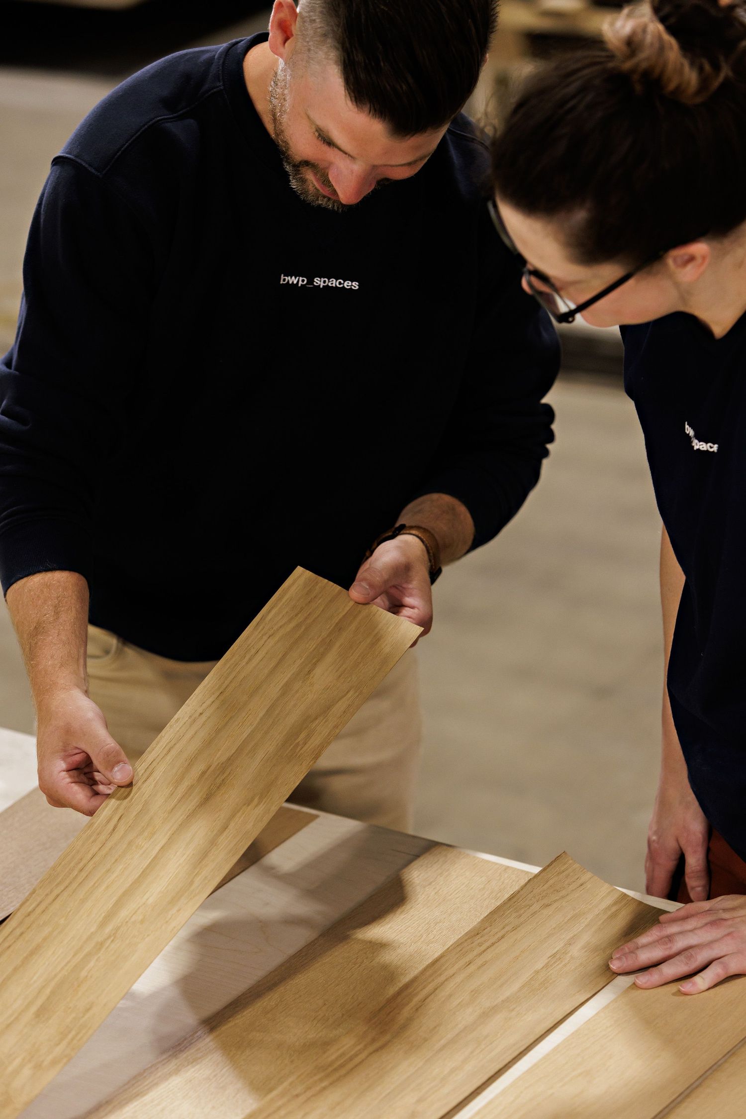 Close-up view of hands examining and inspecting a light wood surface for quality control.