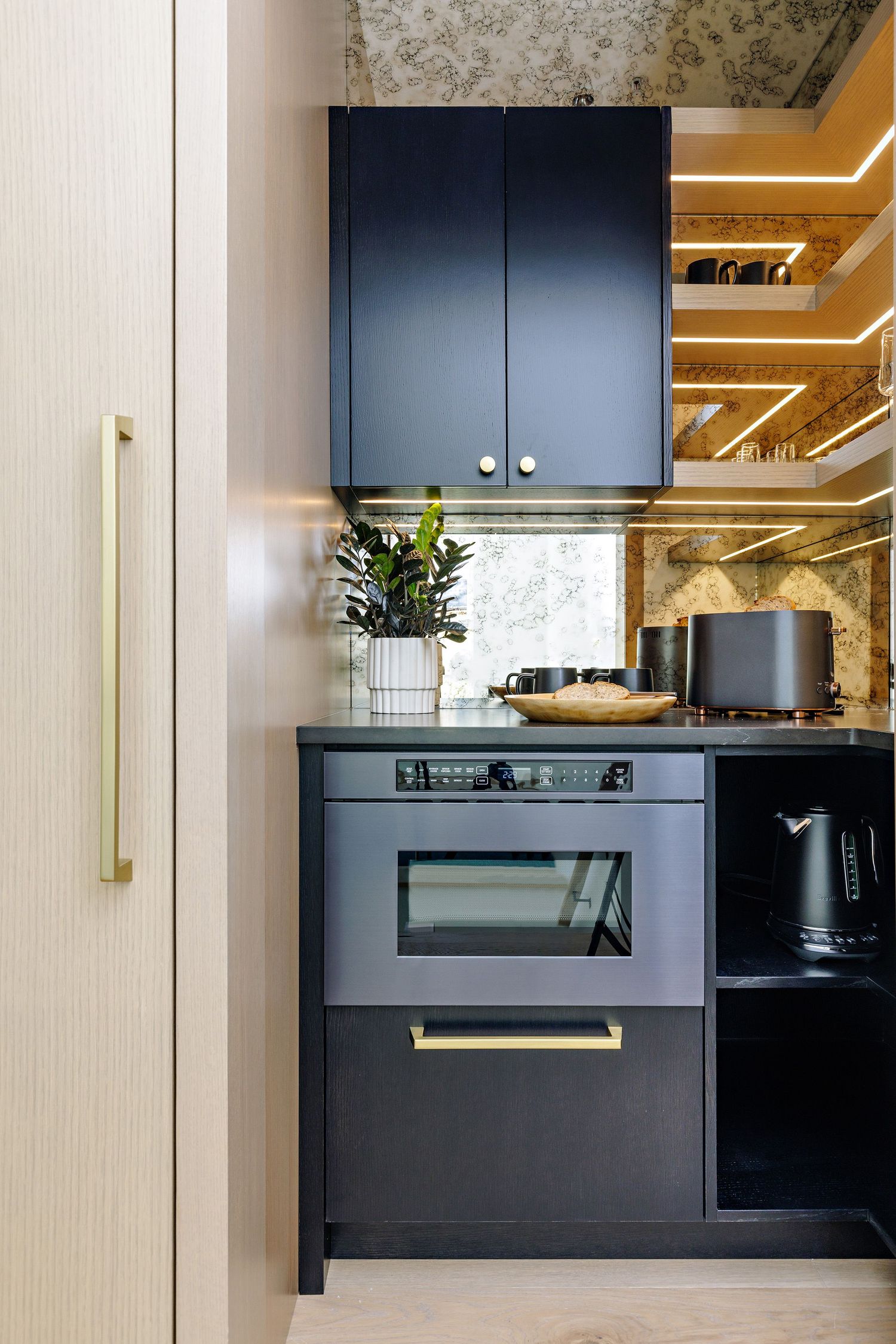 Modern kitchen with navy cabinets, built-in appliances, and gold hardware accents.