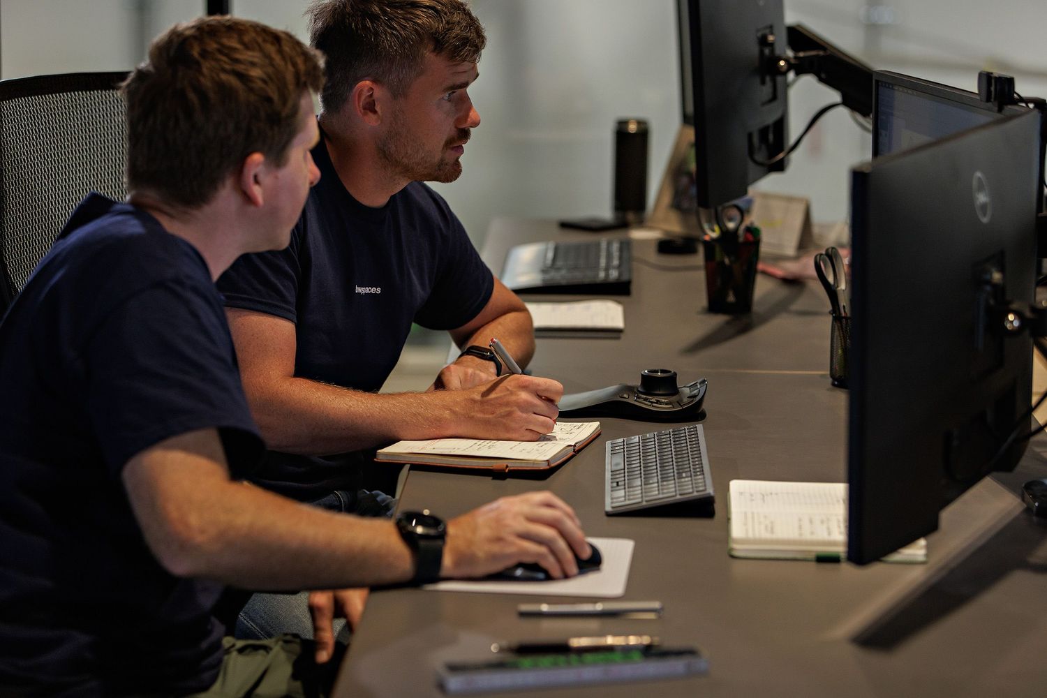 People working at computer workstations in a dark office environment.