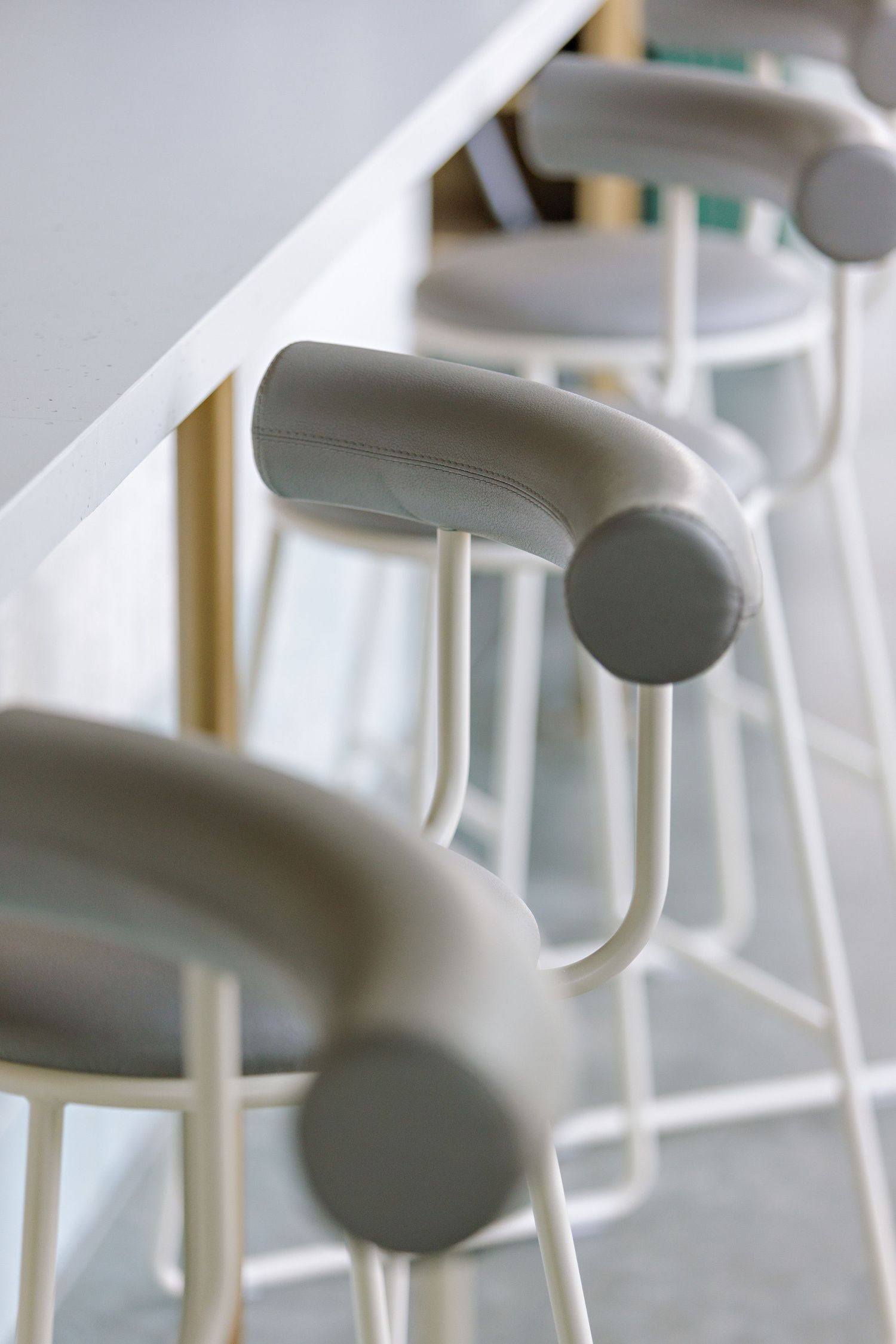 Modern white barstools with curved backrests and sleek metal frames create a minimalist seating arrangement.