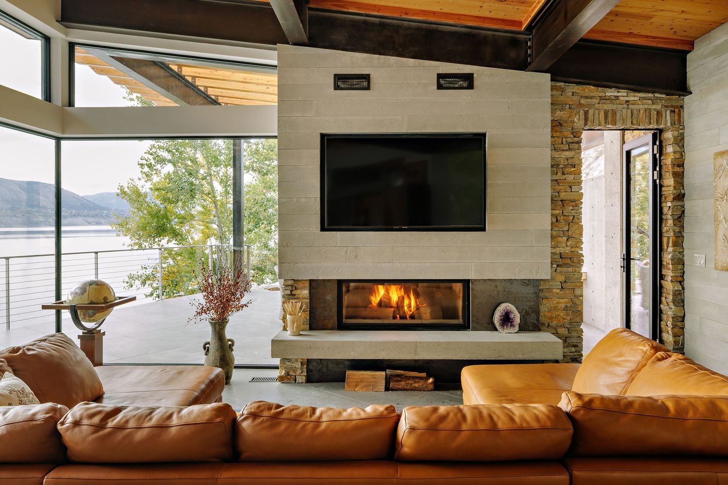 Modern living room features brown leather sectional sofa and sleek fireplace with wood beam ceiling details.