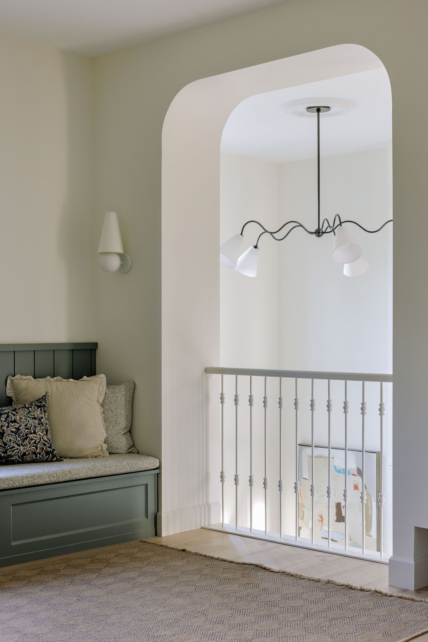 Cozy reading nook with built-in bench seating and modern pendant light under an arched doorway.