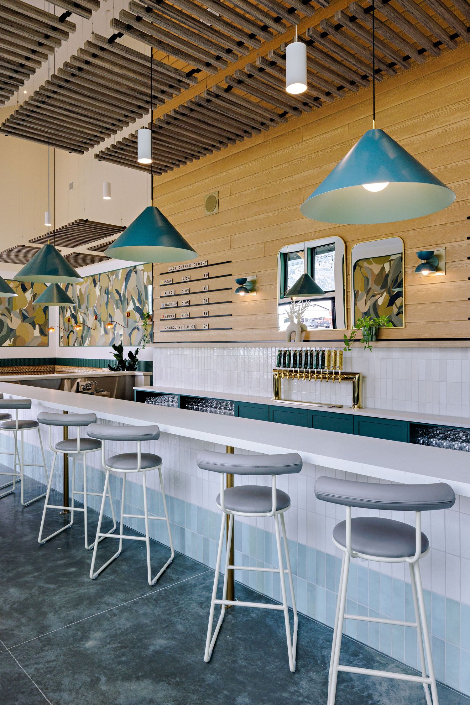 Contemporary restaurant bar with blue pendant lights, white bar stools, and wooden slat ceiling designs.