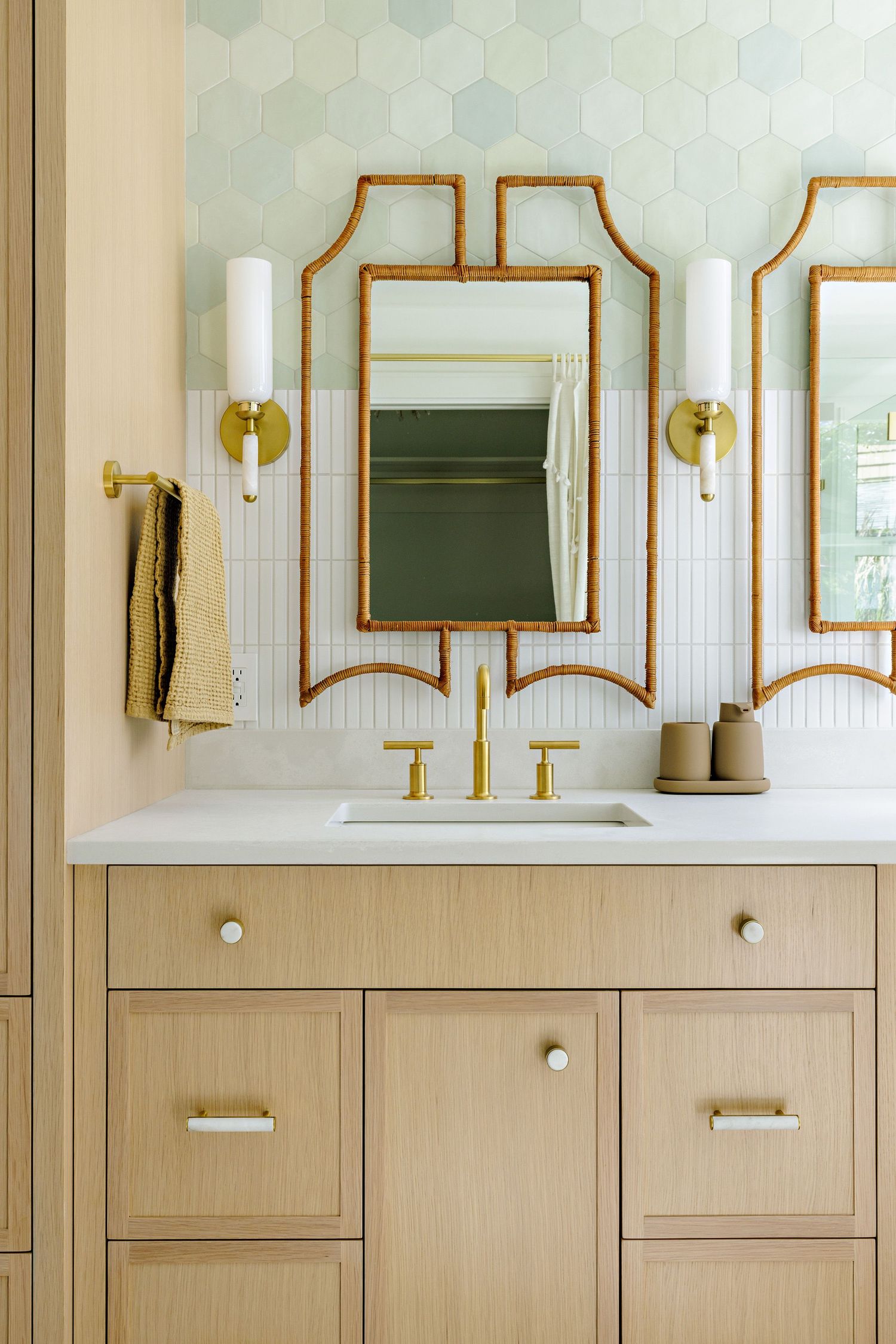 Modern bathroom vanity with geometric gold mirror, white countertop, and beige cabinet doors.