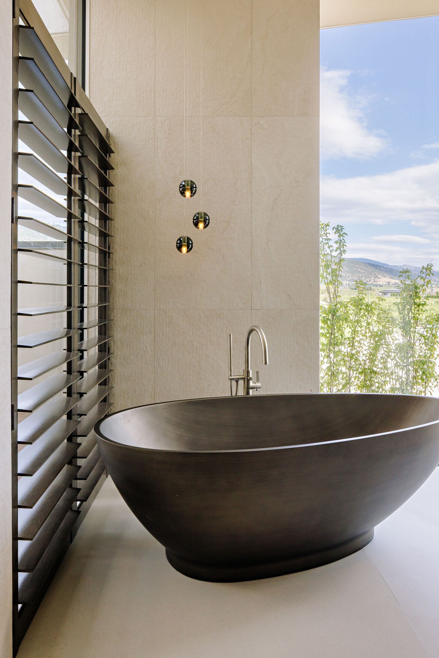 A series of black modern bathtubs shown against white walls with louvered windows and mountain views in the background.