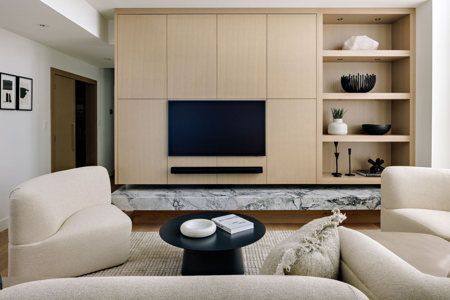 Modern living room featuring built-in media wall with light wood panels and cream sectional seating.