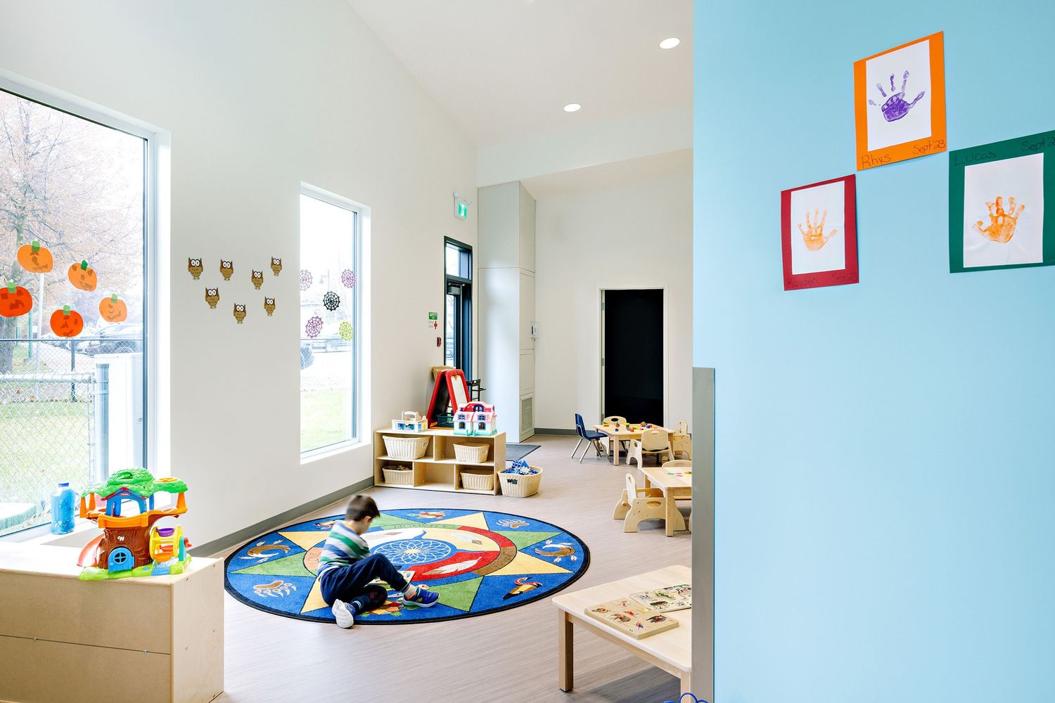Bright modern classroom interior with colorful artwork displays and learning materials on white walls.