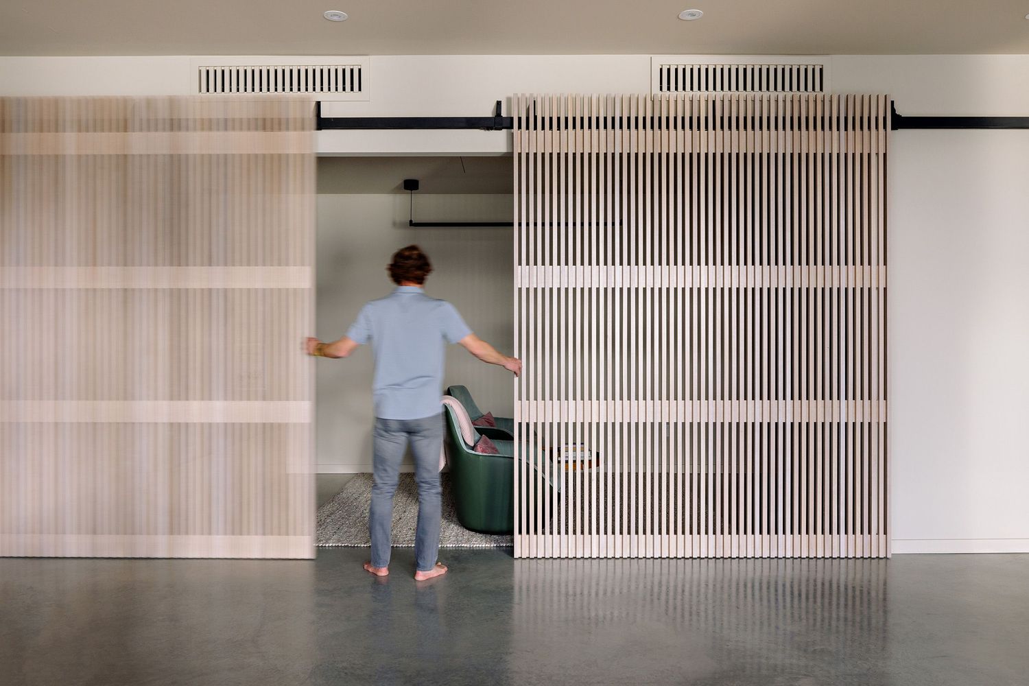 Person standing in front of modern sliding doors with vertical slat pattern in contemporary minimalist interior.