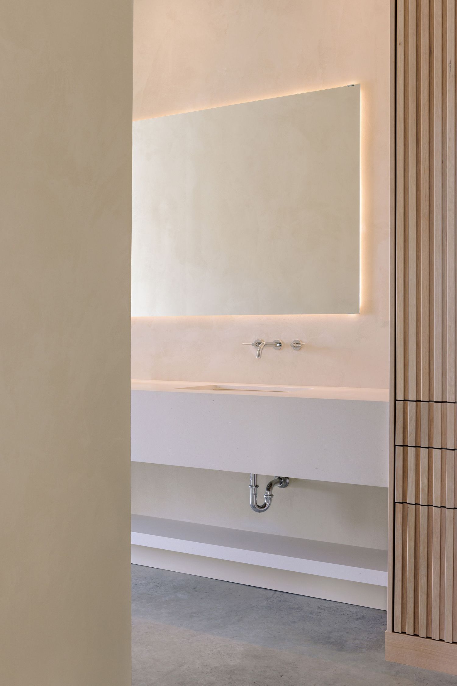 Minimalist bathroom design with floating vanity, backlit mirror, and vertical wood slat accent wall details.