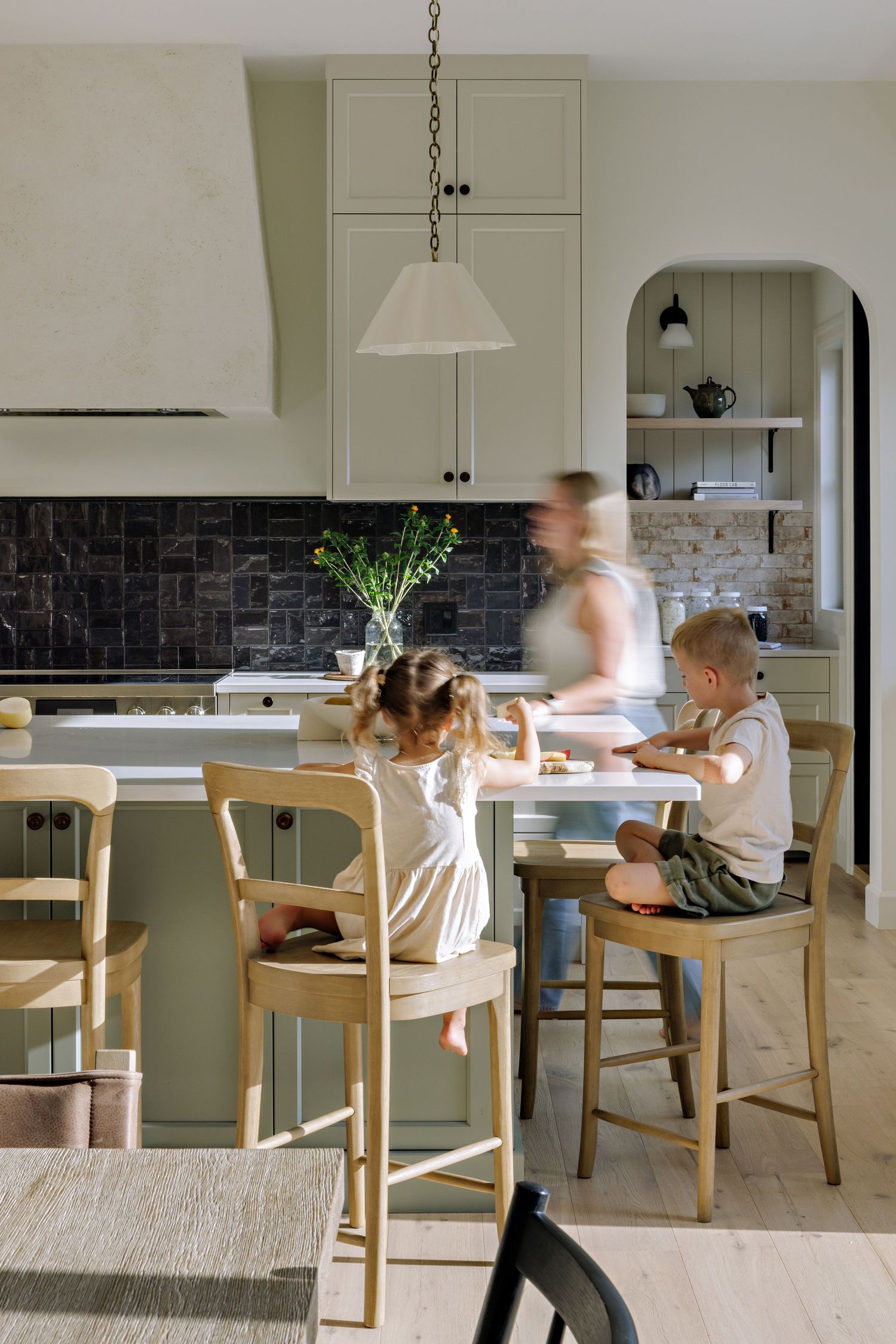 A sequence of motion blur photos showing activity around a wooden dining table in a modern white kitchen.
