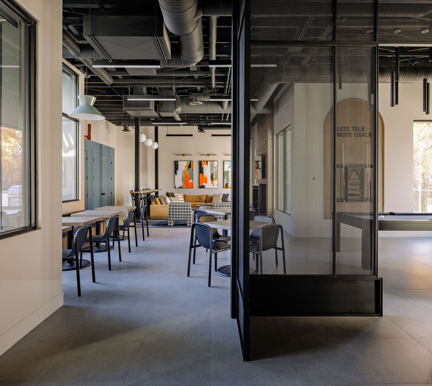 Empty industrial office space with exposed ceiling and concrete floors shows a long corridor with glass partitions.