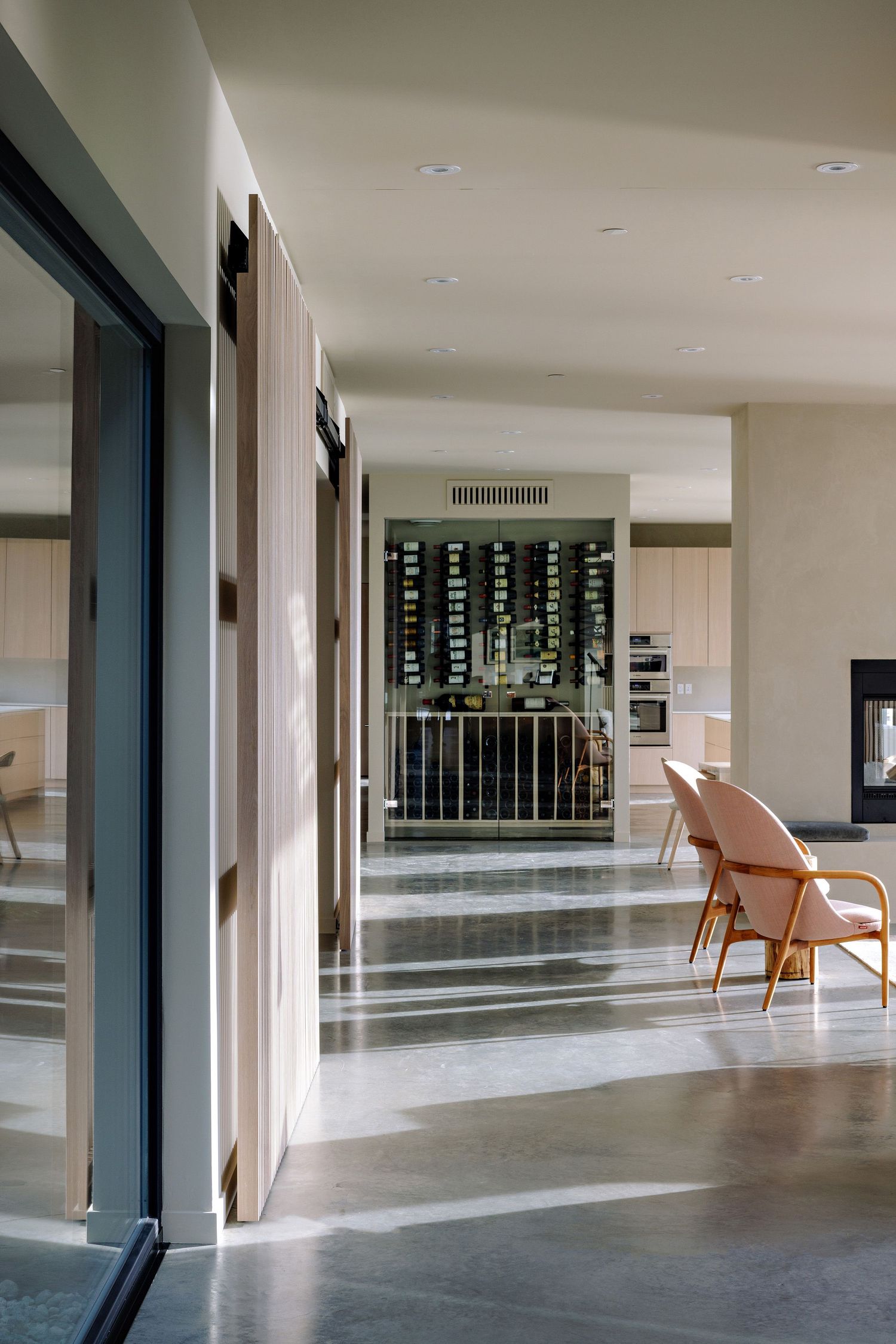 Contemporary interior space with polished concrete floors and a built-in wine display wall visible through doorways.
