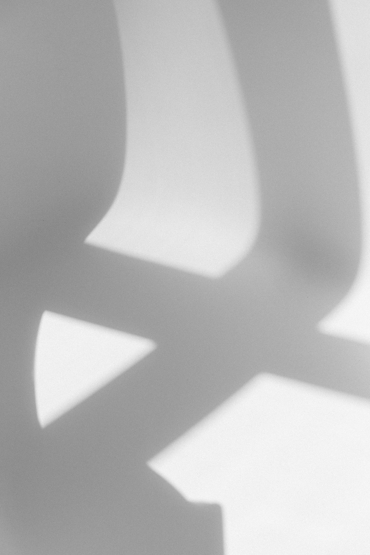 Minimalist abstract shadows and light creating geometric shapes on white surface.