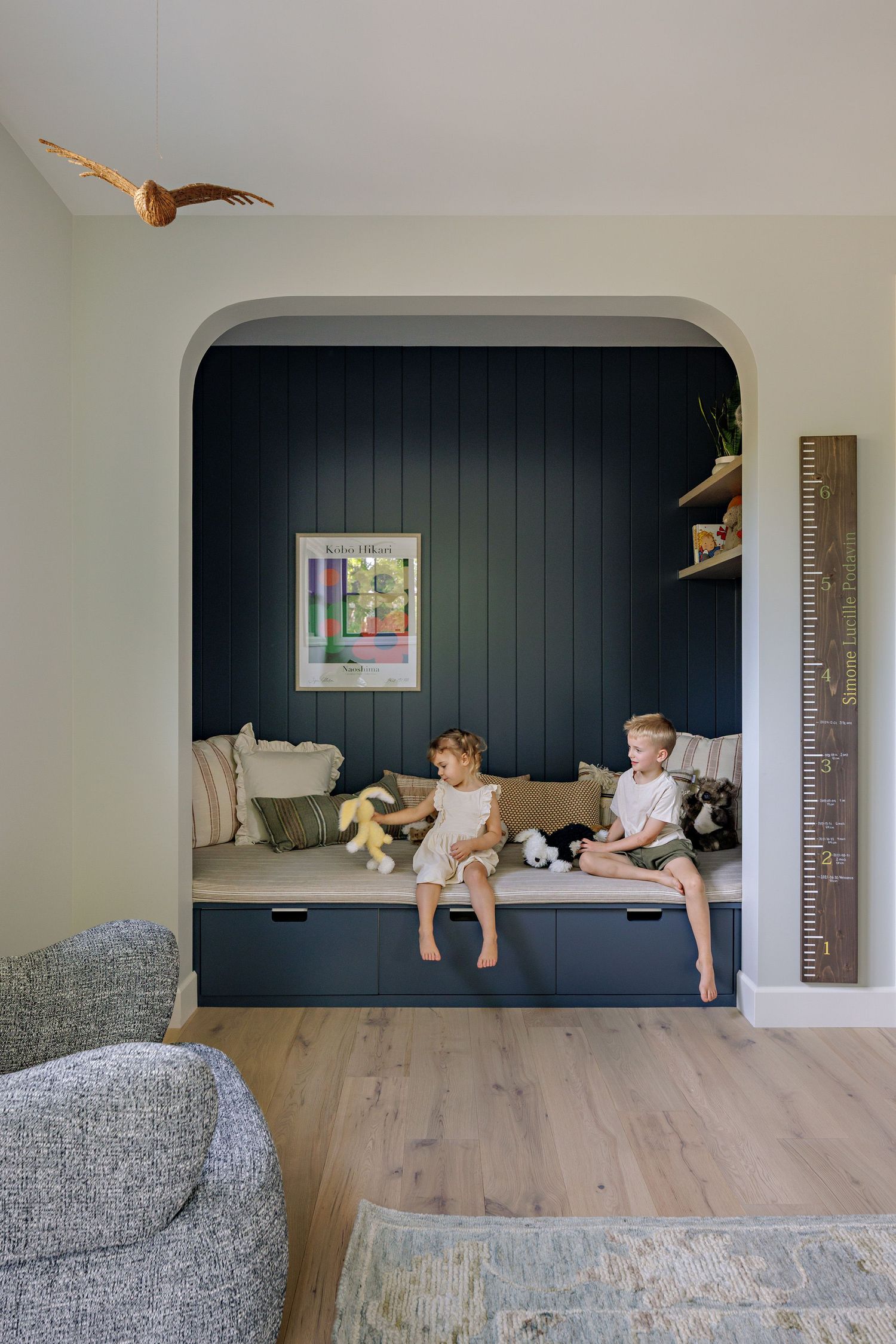 A series of photos showing children playing and jumping on a modern gray couch against a dark navy accent wall.