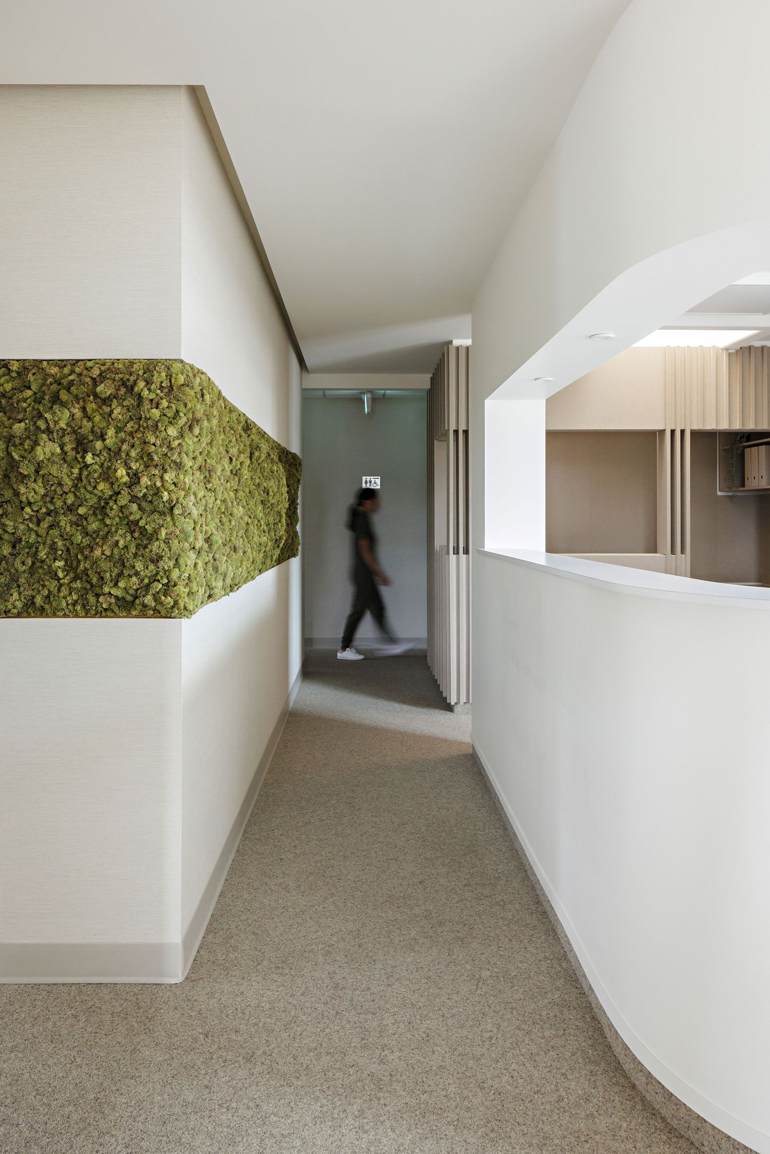 A sequence of minimalist hotel corridor views showing white walls, carpet flooring, and a person walking in the distance.