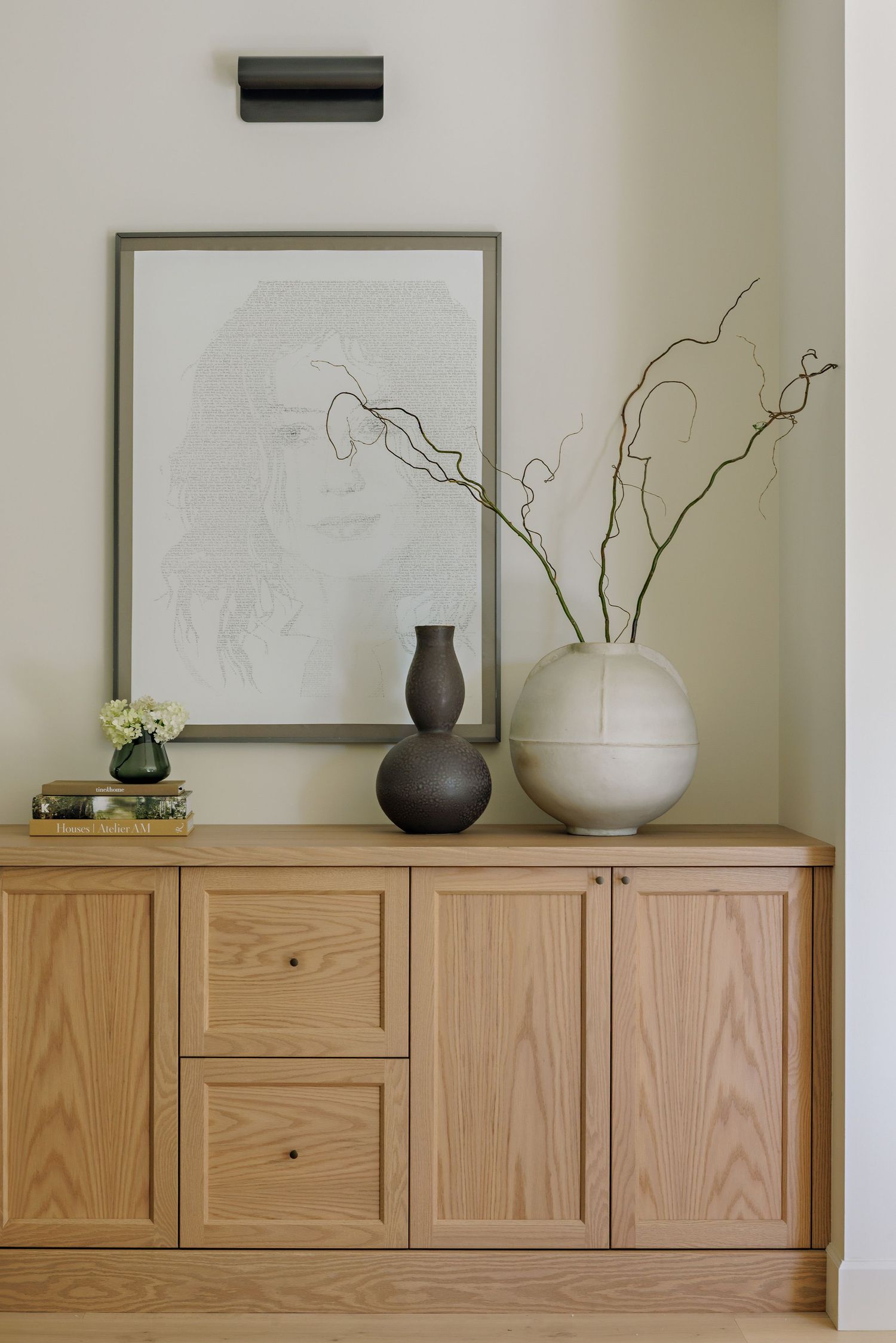 Minimalist wooden sideboard with decorative vases and artwork displays a modern Scandinavian aesthetic.