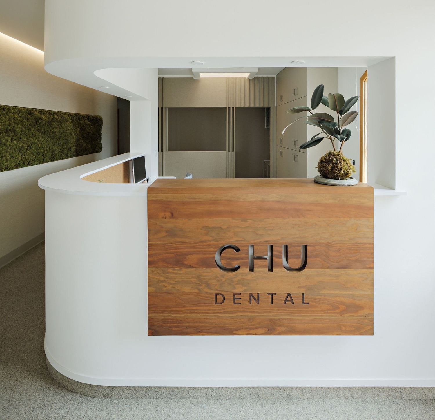 Modern dental office reception desk with wooden CHU Dental signage and minimalist white curved counter design.