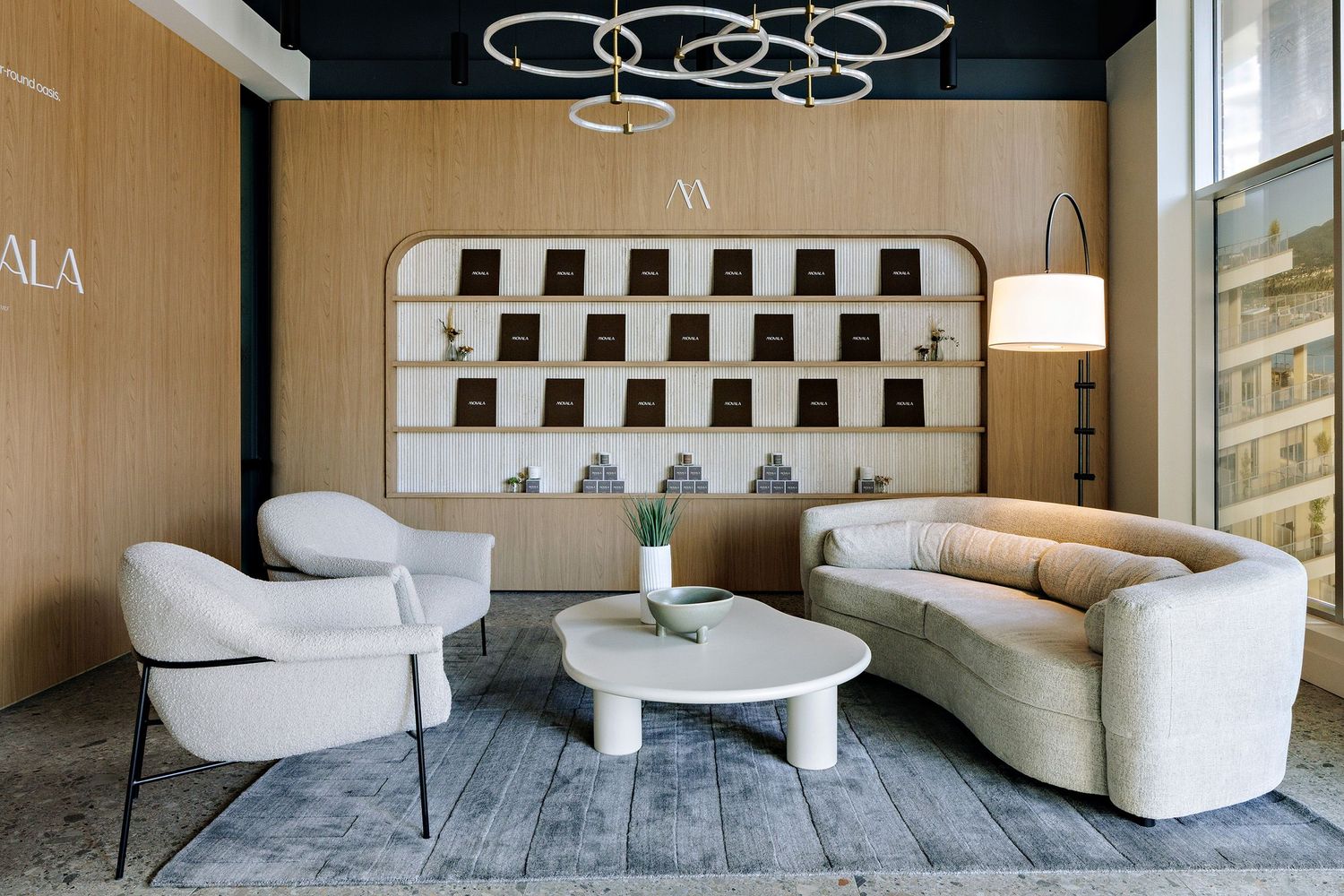Modern lounge area with curved cream chairs, round coffee table and geometric wall decor in luxury interior setting.