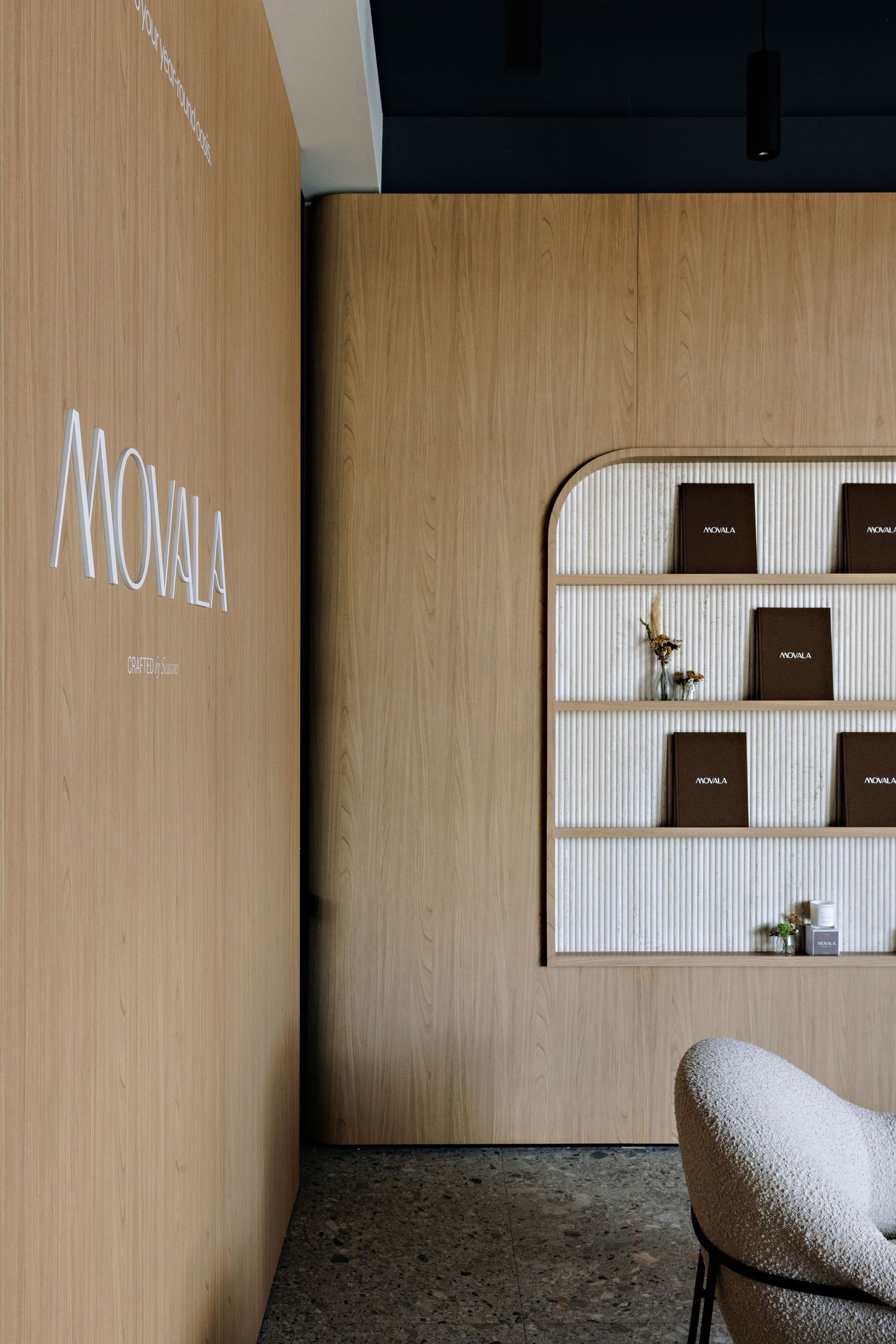Modern interior with 'MONKA' text on beige wall features built-in shelving with books and minimalist decor.