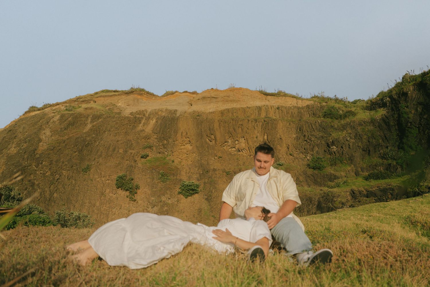 Panoramic view of couple in wedding attire against golden hillside landscape.