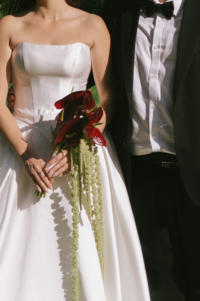 Row of elegant white wedding dresses with cascading floral bouquets.