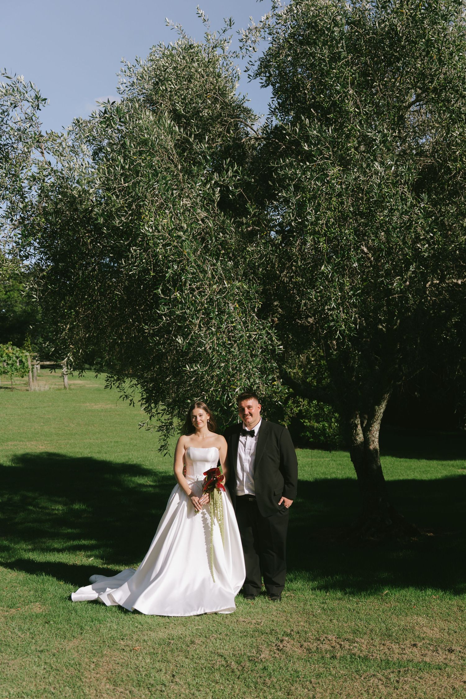Wedding photoshoot in an apple orchard with couple posing among trees.
