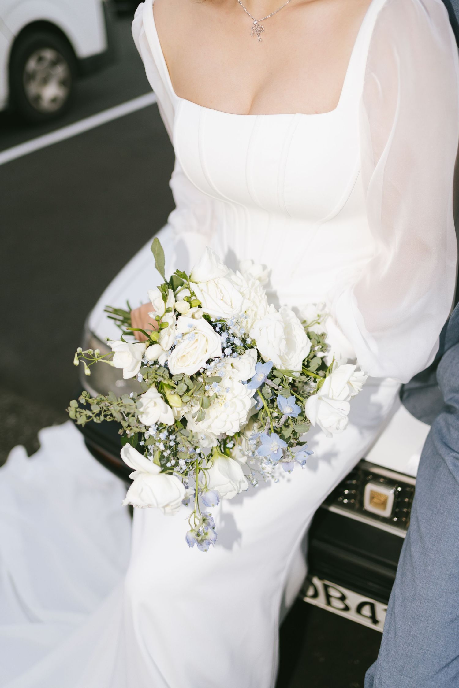 White bridal gown adorned with delicate floral arrangements in soft whites and greens.