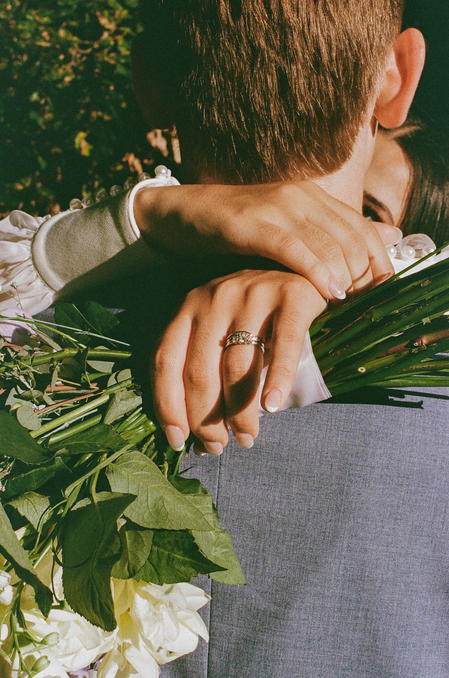 Close-up shots of hands arranging white flowers and greenery on a gray surface.