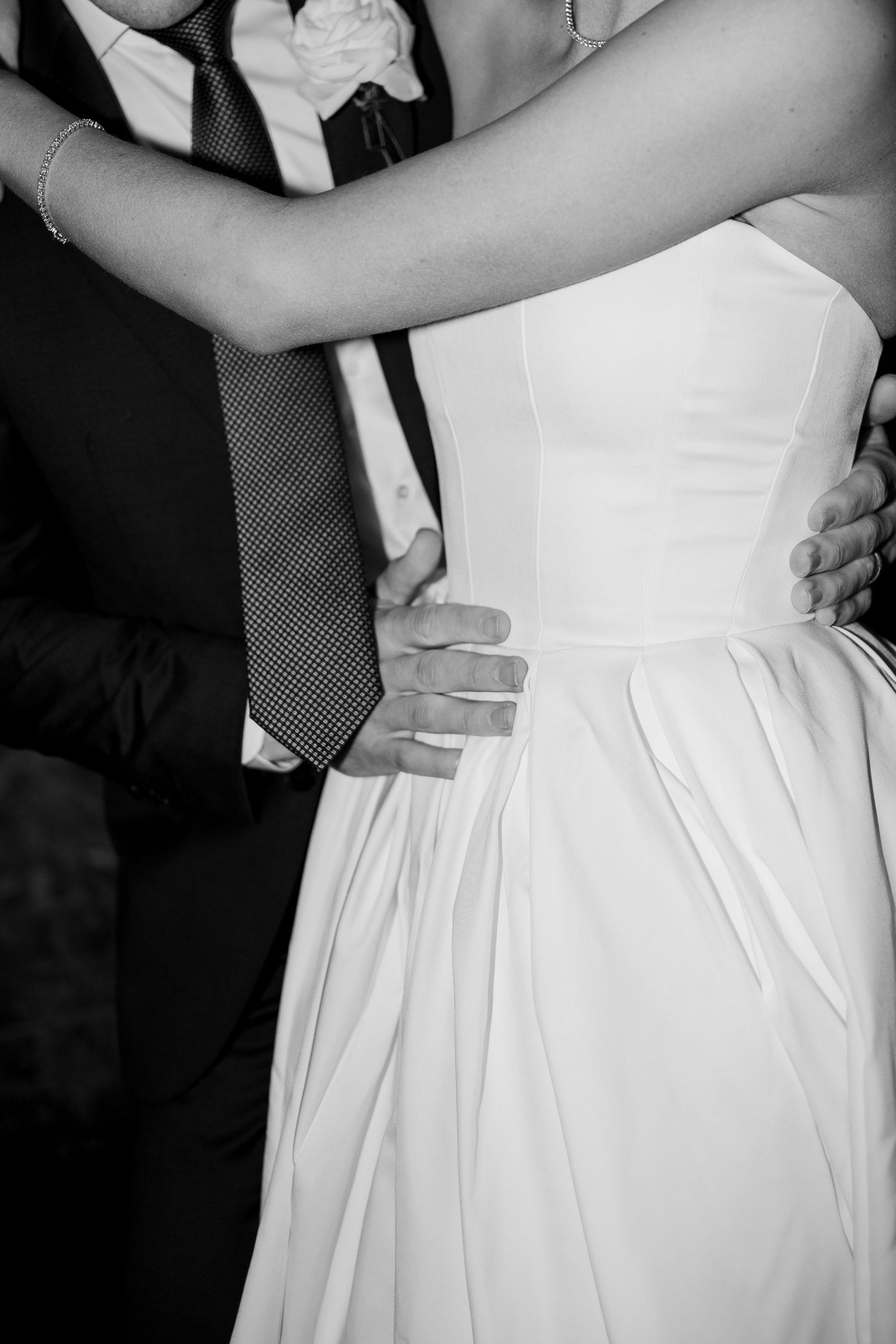 Elegant pleats and tailoring details of a white wedding dress shown in black and white.