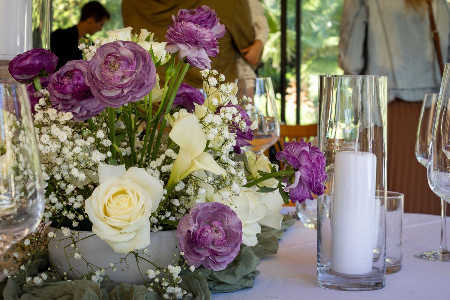 Elegant table setting with purple and white floral centerpieces, glowing candles, and crystal glassware at a formal event.