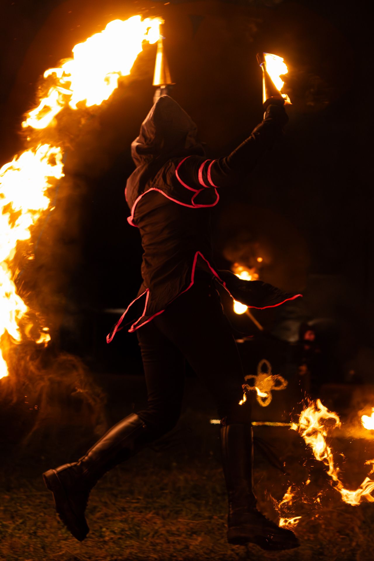 A sequence of fire performers spinning flaming torches in the darkness creating dramatic light trails and silhouettes.