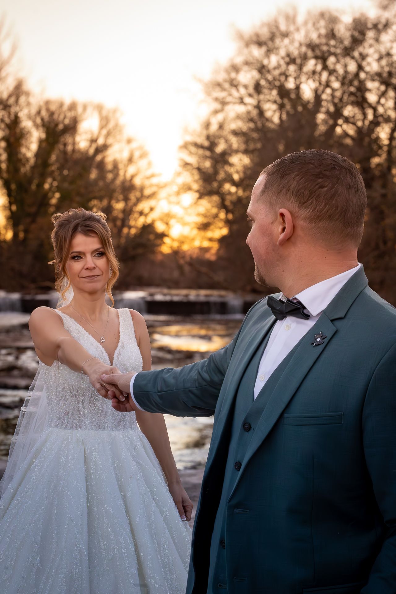 A romantic wedding couple shares an intimate moment at sunset with snow on the ground.