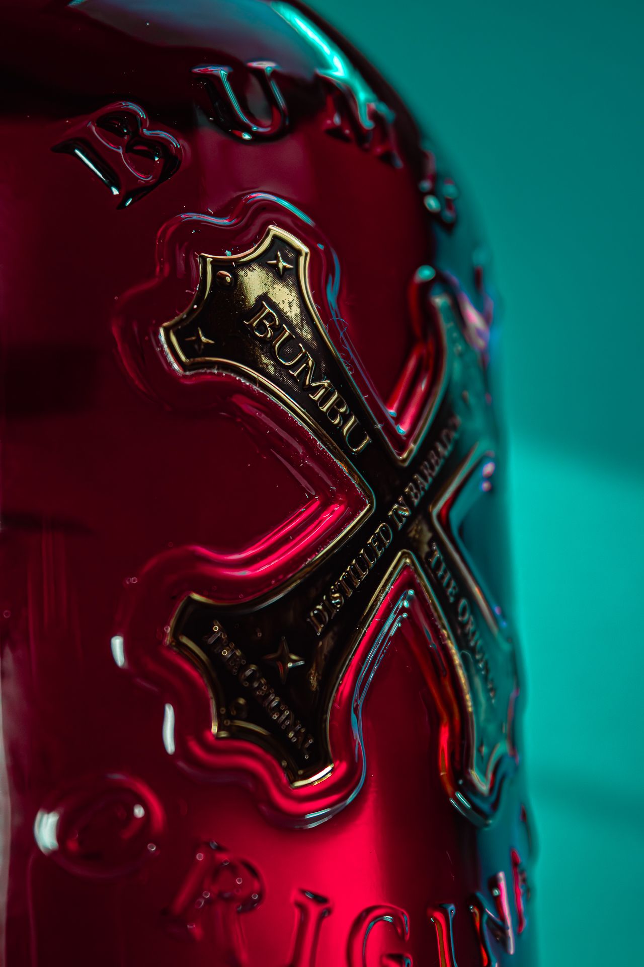 Close-up macro shots of a red wine bottle with metallic label details against a teal background.