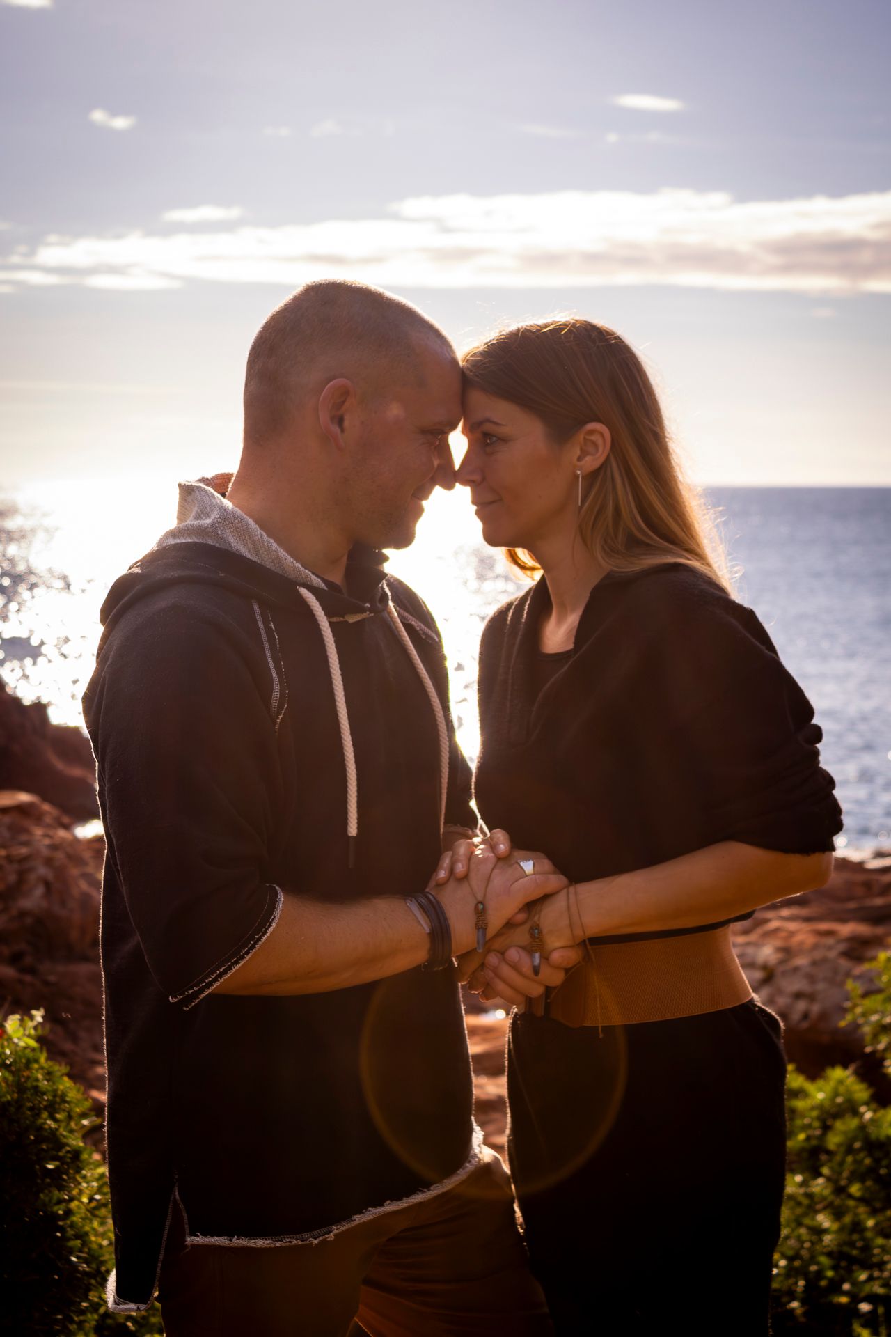 Silhouetted couple embraces against a dramatic sunset over the ocean, creating a romantic seaside moment.