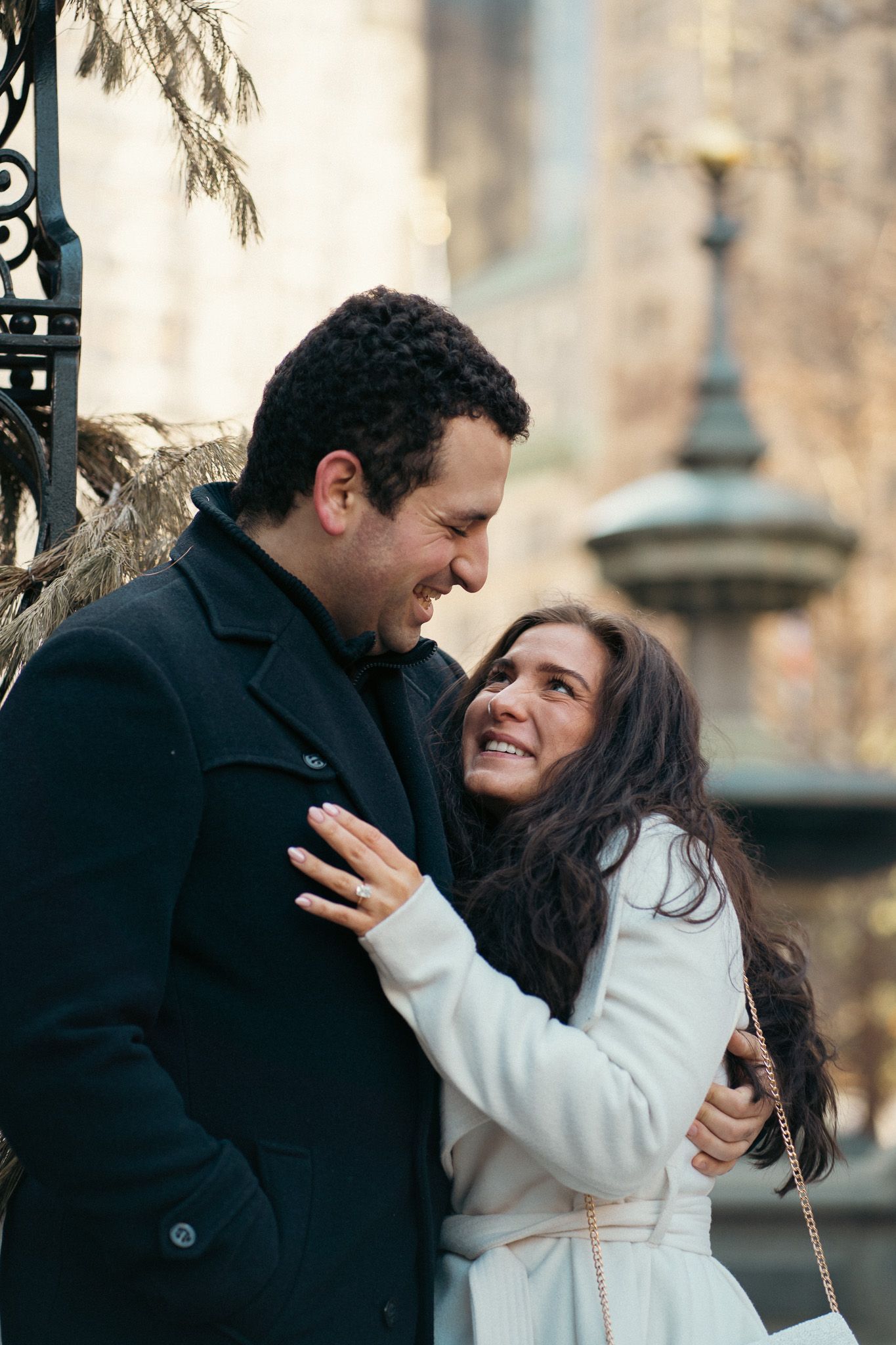 A romantic couple sharing intimate moments and laughter while embracing outdoors on a winter day.