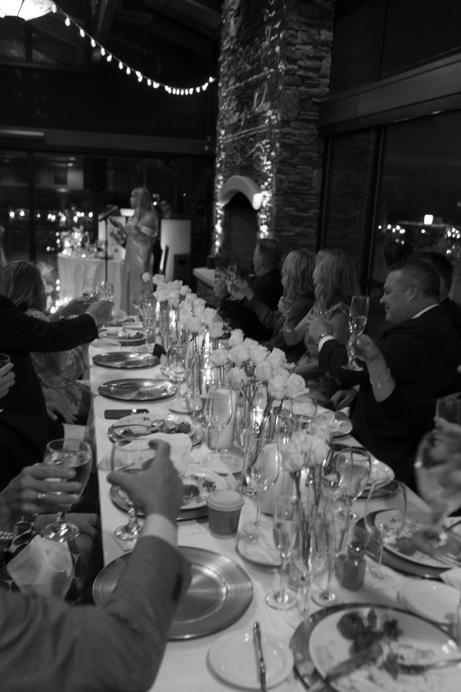 A black and white photo of an elegant dinner table setting with glowing candles and glassware extending into the distance.