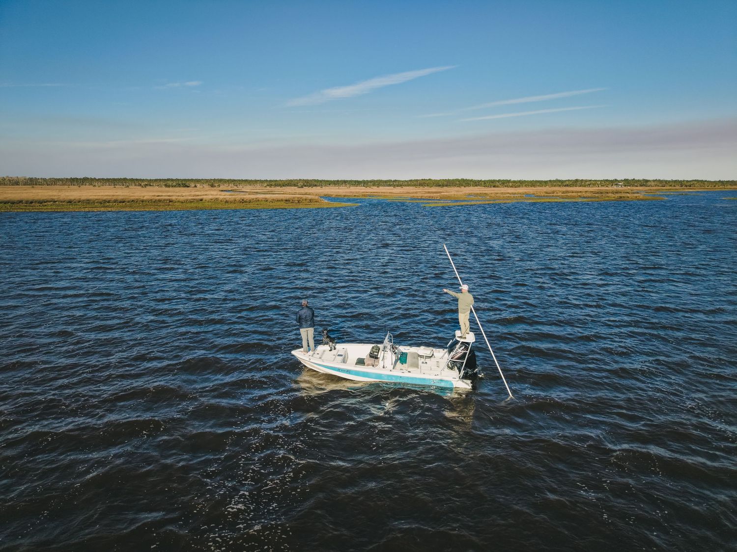 Small fishing boat navigating through coastal waters on a clear sunny day.