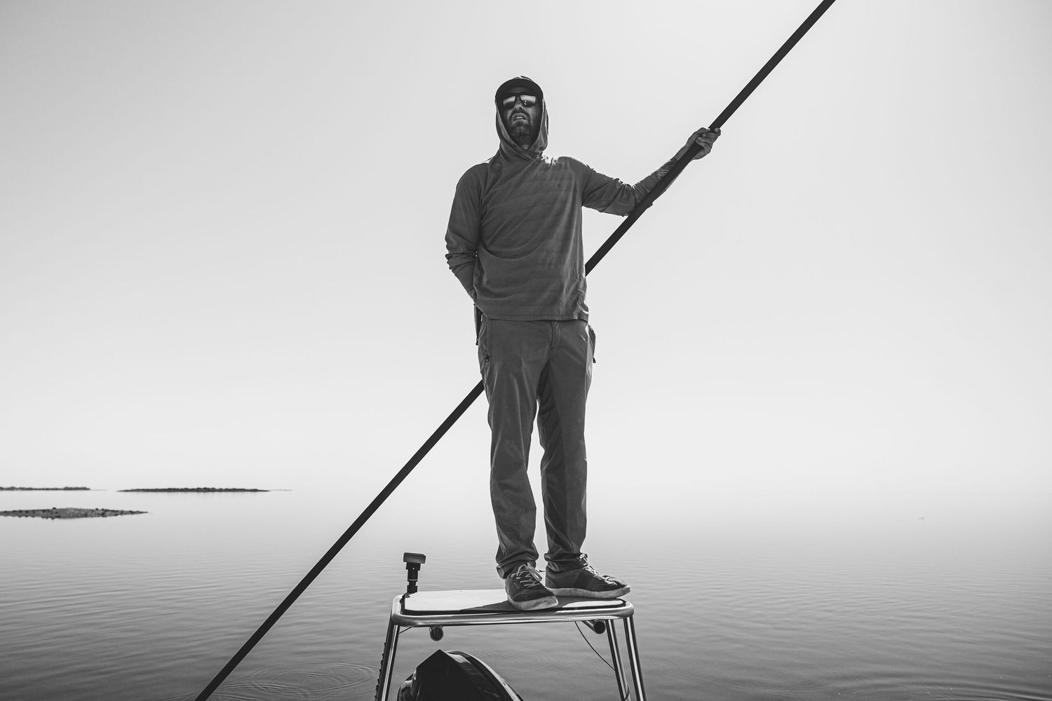 Silhouette of angler holding fishing rod against white background.