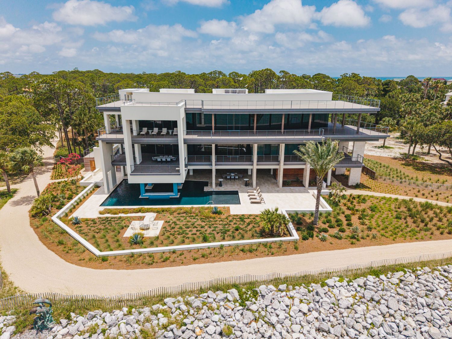 Modern luxury beachfront home with pool and landscaped grounds overlooking the ocean.