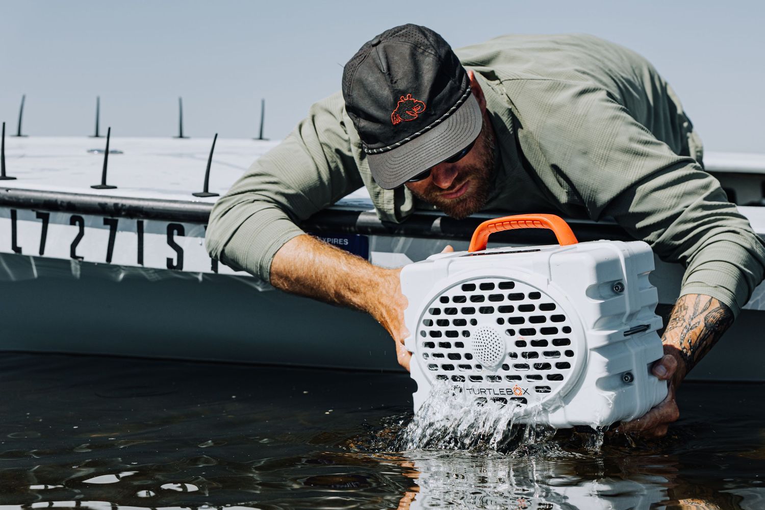 Close-up of hands submerging white waterproof speaker in clear water.